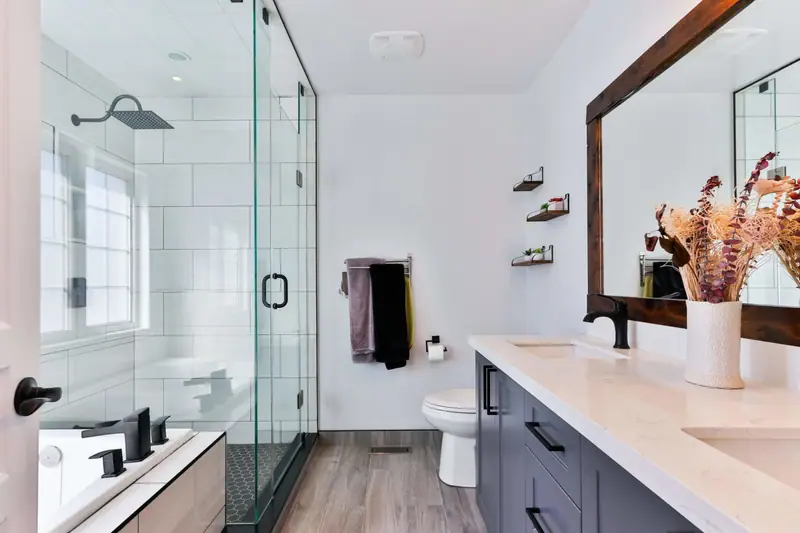 Remodeled bathroom with frameless glass shower, matte black fixtures and dark navy vanity