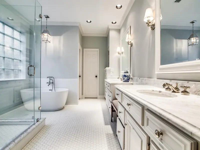 Bright primary bathroom with freestanding tub, glass shower and white vanity
