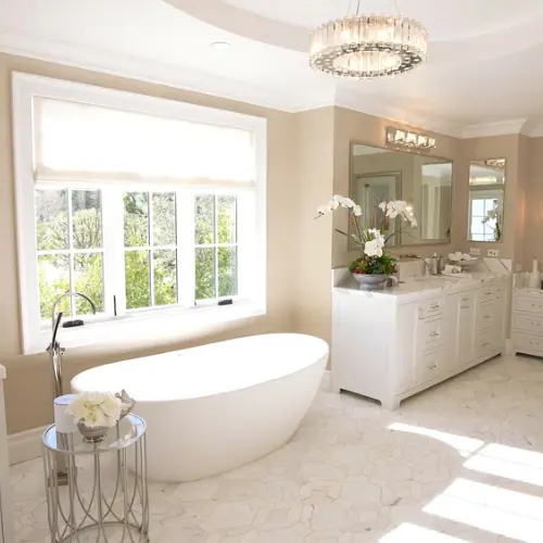 Sunny bathroom with freestanding tub, white vanity and window wall