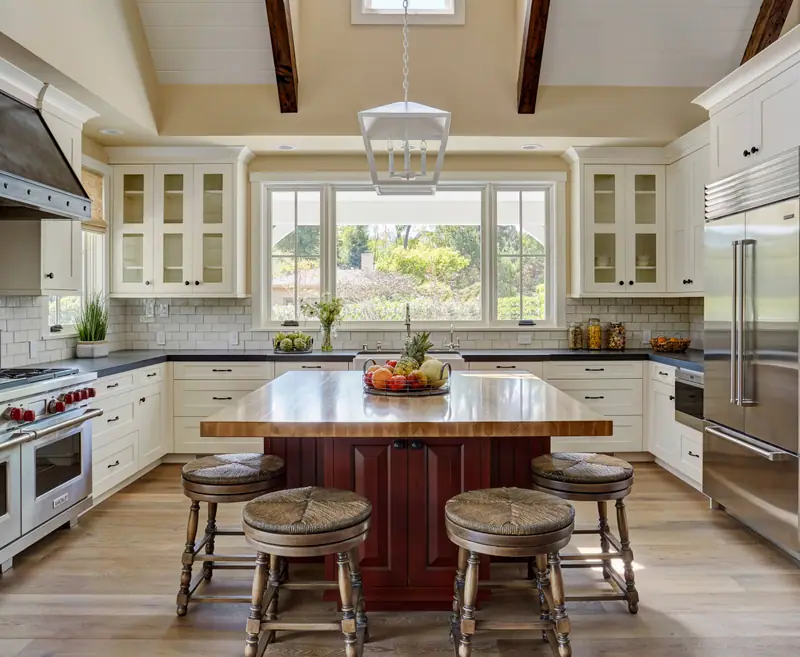 Traditional cream kitchen with glass-front cabinets, red painted island and butcher-block top