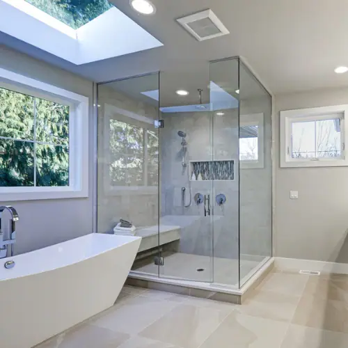 Glass shower enclosure with bench next to a freestanding tub
