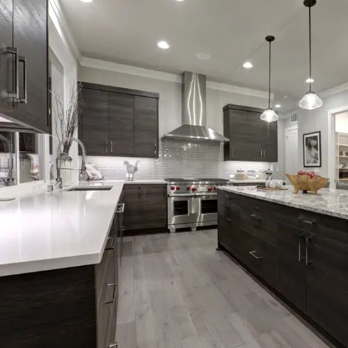 Kitchen with dark wood cabinets, white quartz countertops and stainless chimney hood