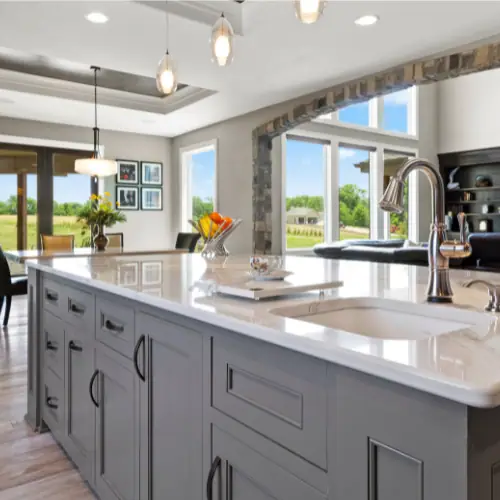 Kitchen with gray shaker island, quartz top and pendant lighting over seating
