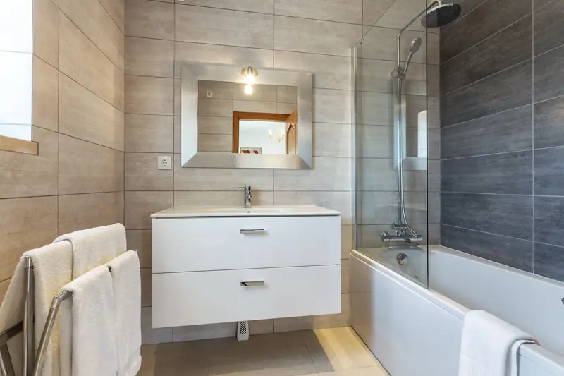 Modern bathroom with floating white vanity, large-format tile and tub-shower combo