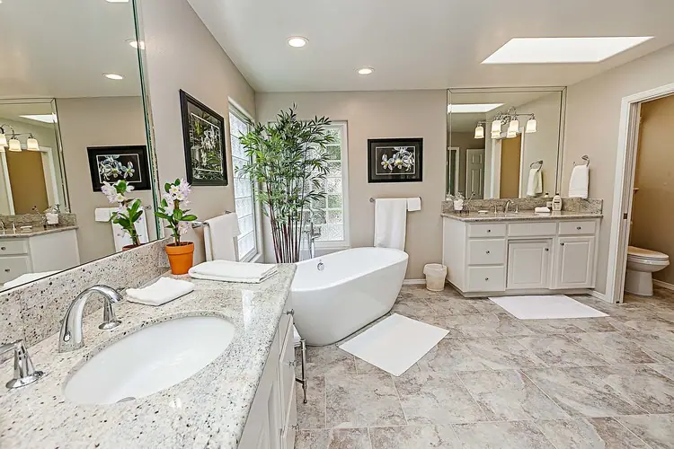 Primary bath with granite double vanity, soaking tub and porcelain tile floor