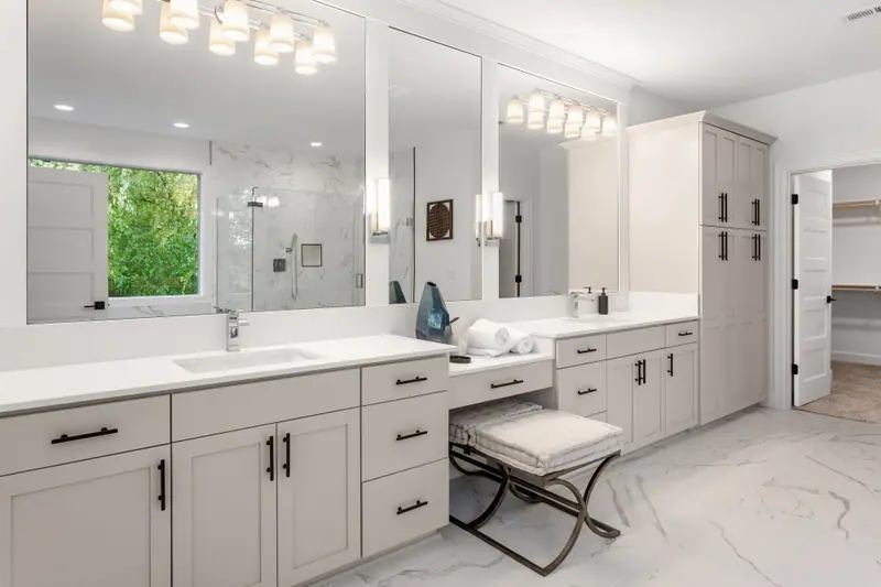 White double vanity with makeup station, quartz top and marble-look floor tile