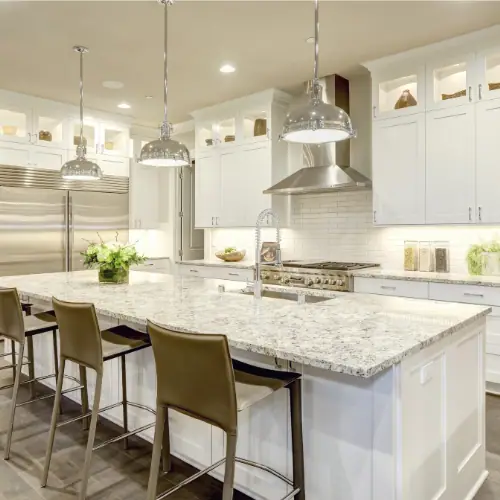 White kitchen with glass-front upper cabinets and a large granite island