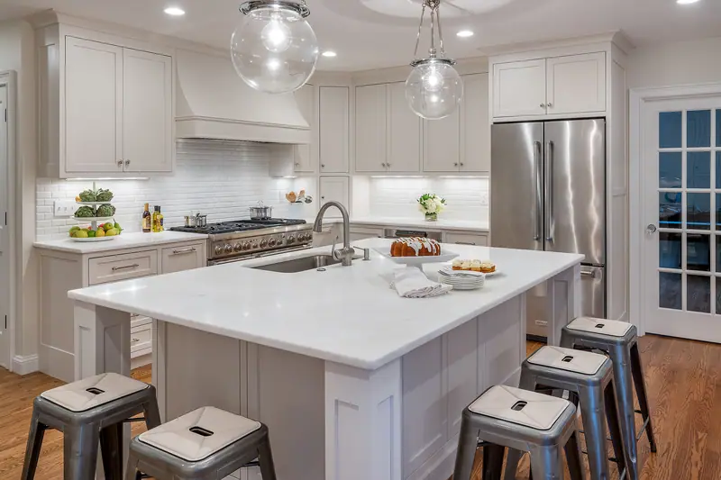 Bright white kitchen with a large island, glass globe pendants and stainless appliances