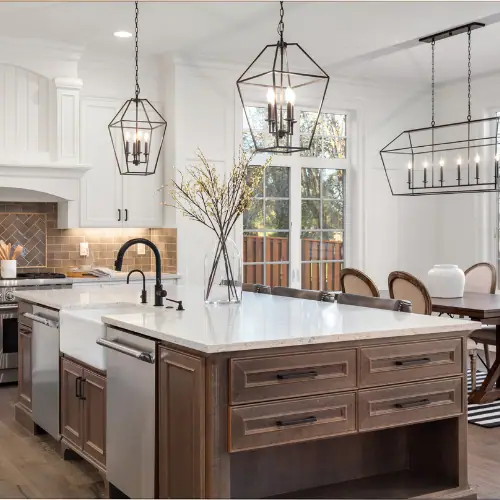 White kitchen with stained wood island, farmhouse sink and black lantern pendants